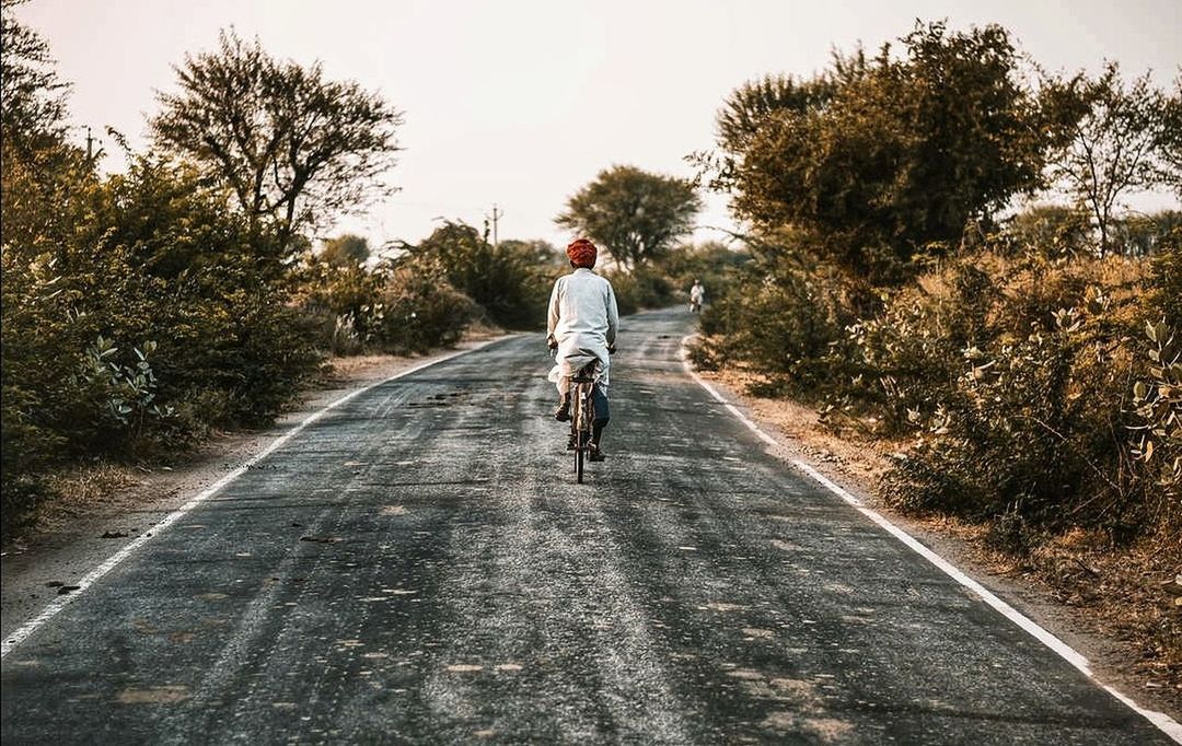 tree, real people, transportation, plant, one person, lifestyles, leisure activity, road, the way forward, ride, riding, direction, rear view, nature, casual clothing, full length, land vehicle, bicycle, mode of transportation, outdoors, diminishing perspective