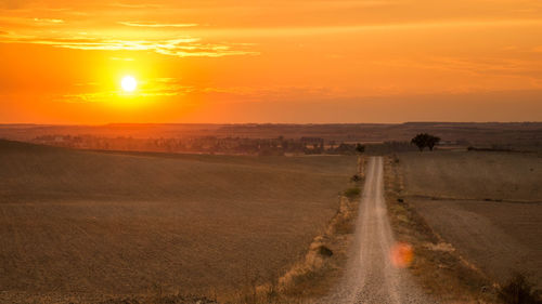 Scenic view of field against orange sky