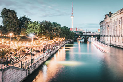 Scenic view of restaurant next to river against cloudy sky