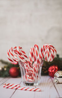 Close up of glass full of candy canes against christmas backdrop.