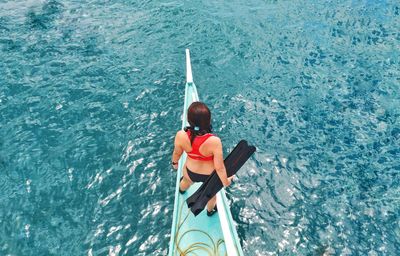 High angle rear view of woman standing on boat in sea