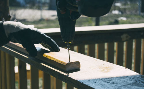 Cropped hand of worker drilling screw on wood