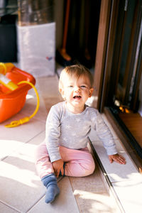 Cute baby girl sitting on floor at home