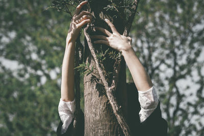 Midsection of woman holding tree trunk