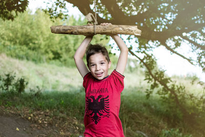 Portrait of happy boy playing with wooden swing