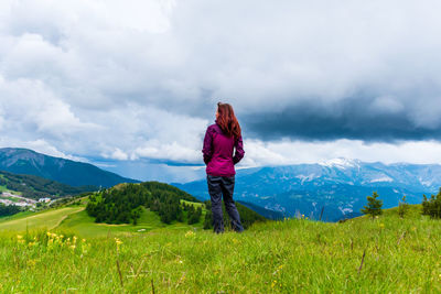 A young female hiker on a break during a hike on a cloudy summer day in the french alps