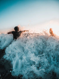 Man splashing water in swimming pool against sky