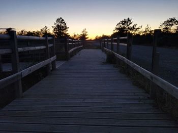 Boardwalk leading towards trees at sunset