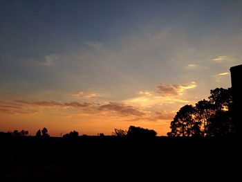 Silhouette trees on landscape against sky at sunset