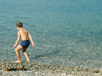 Full length of shirtless boy standing on beach