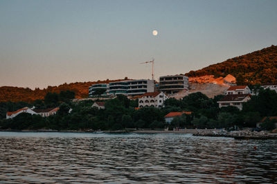 Scenic view of lake by buildings against clear sky