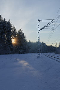 Snow covered field against sky during sunset