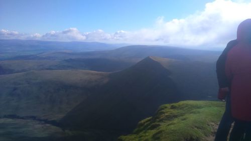 Rear view of man standing on mountain against sky