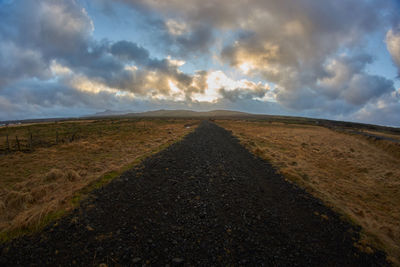 Road amidst field against sky