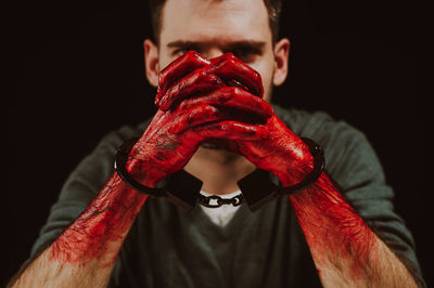 Cropped hand of man holding hands against black background