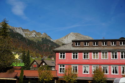 Low angle view of buildings and mountains against blue sky