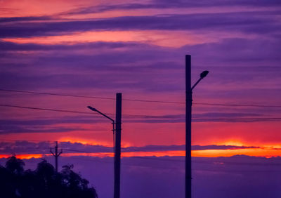 Silhouette electricity pylon against dramatic sky during sunset