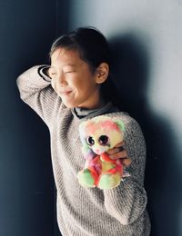 Smiling boy with toy standing against wall