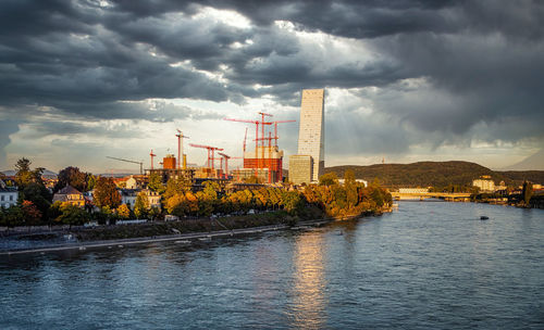 Factory by river against sky