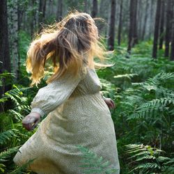 Side view of young woman standing in forest