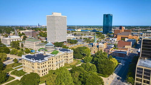 High angle view of buildings in city against clear blue sky
