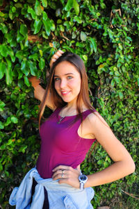 Portrait of beautiful woman smiling while standing against plants