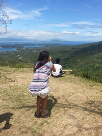 Rear view of woman standing on landscape against sky