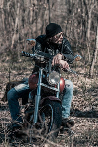 Full length of mid adult man sitting on motorcycle in forest