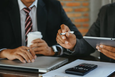 Midsection of businessman using laptop on table