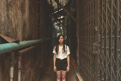 Portrait of young woman standing in alley