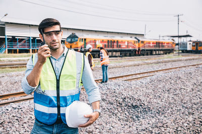 Portrait of young man standing on railroad track