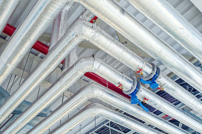 Metal pipes mounted under ceiling are covered with thermal insulation at modern production plant