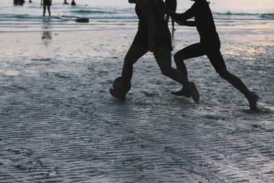 Low section of man walking on wet beach