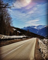 Empty road by snowcapped mountains against sky