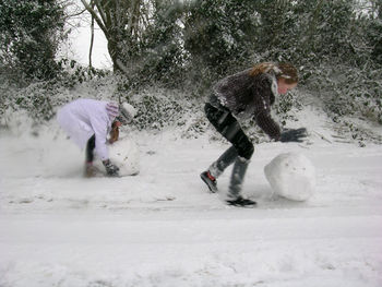 Two girls rolling large snowballs