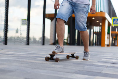 Hipster skateboarding in city with one foot placed on board and pushing off with the other