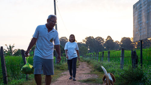 Senior couple by dog walking on footpath