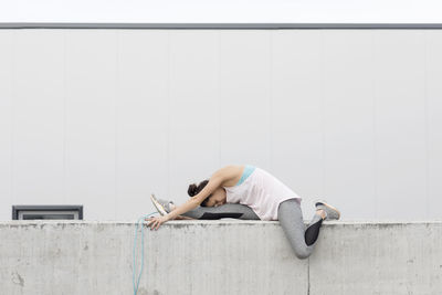 Full length of woman stretching legs on terrace