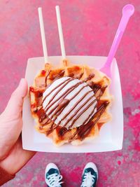 Close-up of hand holding ice cream cone with waffle in plate