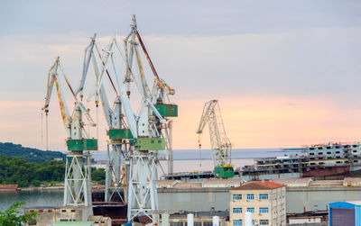 Cranes at harbor against sky