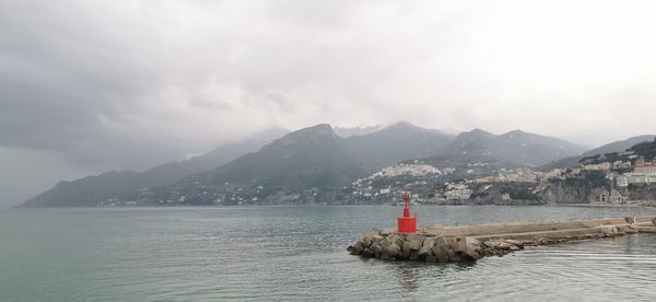 Lighthouse by sea against sky