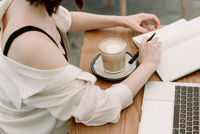 Midsection of woman holding coffee cup on table