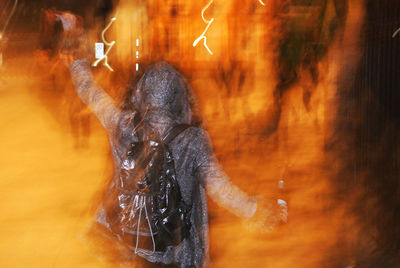 Digital composite image of hooded person and burning fire