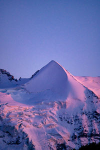 Aerial view of snowcapped mountains against clear blue sky