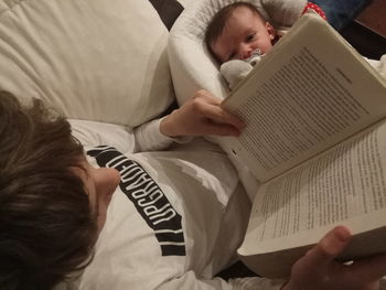 High angle view of baby hand on book at home