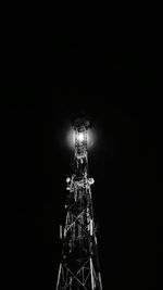 Low angle view of illuminated tower against black background