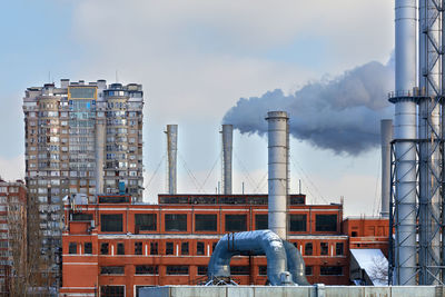 Smoke chimneys from the city thermal station against the background of residential buildings. 