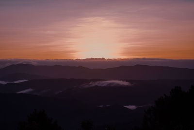 Scenic view of silhouette mountains against orange sky