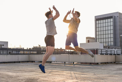 Friends playing basketball at sunset on a rooftop