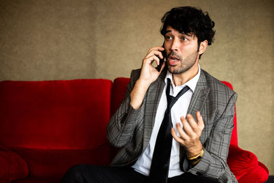 Young man using mobile phone while sitting on sofa